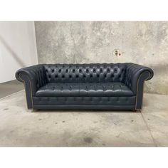 a black leather couch sitting on top of a cement floor