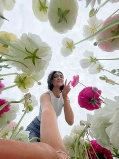 a woman standing in front of flowers with her hand up