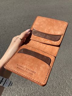 a person holding two brown wallets in their hand