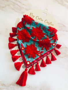 a red and blue bandana with tassels on it sitting on a marble surface