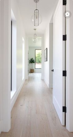 an empty hallway with white walls and wood floors