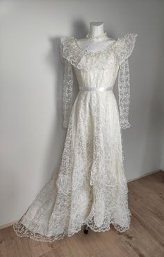 Long wedding gown from 89s in victorian style. Frills in top and bottom. Flower lace all over the dress. In waist white ribbon. On the back bow, zip fastener, medium long tail. Size rather XS but please check belowe. Measurement taken flat and doubled: Bust 82 cm Waist 62 cm Lenght im front 134cm Cream Floor-length Gown With Lace Trim, Elegant Long Sleeve Wedding Dress With Lace Trim, Lace Gown With Ruffles For Debutante Ball, Wedding Gown With Lace Sleeves, Long Sleeve Lace Trim Wedding Dress, Long Sleeve Lace Dress For Debutante Ball, Lace Gown With Lace Trim For Debutante Ball, Formal Lace Victorian Dress With Ruffles, Lace Victorian Dress With Ruffles For Formal Occasions