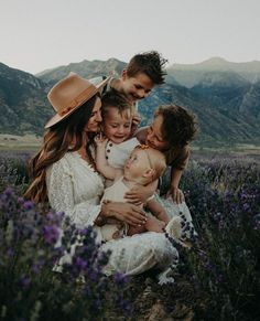 a group of people that are sitting in the grass with one woman holding a baby