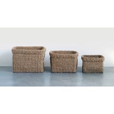 three woven baskets sitting next to each other on the floor in front of a white wall