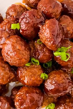 some meatballs are piled on top of each other with green garnishes