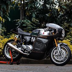 a black motorcycle parked on the side of a road in front of some bushes and trees