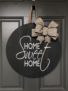 a sign that says home sweet home hanging on a door with a bow attached to it