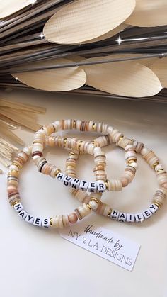 GORGEOUS MESSAGE BRACELETS IN A BEAUTIFUL COLORFUL VARIETY OF SHELL/BONE/WOOD BEADS ACCENTED WITH GOLD SPACER BEADS AND WHITE/BLACK LETTER BEADS.  REFER TO OPTIONS IN PHOTOS.  📍PLEASE NOTE: OUR NY2LA TAG IS NOT INCLUDED WITH EACH BRACELET. THERE IS A COST OF $3.00 per tag. MESSAGE US BEFORE YOU ORDER IF YOU WOULD LIKE OUR LOGO TAG TO SEE STOCK AVAILABILITY  JUST MESSAGE US YOUR WORD OR WORDS  PLEASE DO NOT WEAR IN OCEAN, POOLS OR THE SHOWER.  THIS CAN CHANGE THE COLORS OF THE BEADS Message Bracelets, Word Bracelets, Bracelet Message, Message Bracelet, Word Bracelet, Your Word, Logo Tag, Letter Beads, Black Letter