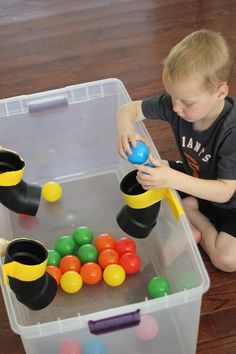 a little boy playing with some sort of toy in a plastic container on the floor