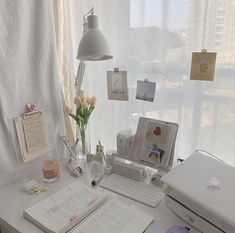 a desk with a laptop, keyboard and flowers on it