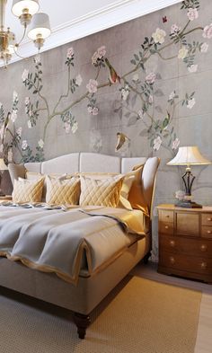 a large bed sitting under a chandelier next to a wall with flowers on it