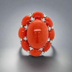 This exquisite ring boasts a striking combination of coral and diamonds, set in 18K white gold. Its bold and beautiful design is perfect for making a statement. The luxurious materials and expert craftsmanship make it a timeless piece to treasure for years to come. Jewelry Style: RingMetal Type : 18K White GoldWeight : 20.76 gramsRing Size : 7Estate - pre-ownedMeasurement : 30 mm x 25 mmCoral Shape : OvalCoral Weight : 25.02 ctQuantity : 9Diamond Shape : RoundWeight : 1.25 cttwColor : IClarity : SI2 This is sold as an estate piece, all weights are estimates. Elegant Orange Diamond Ring With Gemstone, Elegant Oval Coral Rings, Elegant Coral Oval Rings, Elegant Coral Ring Jewelry, Elegant Coral Rings For Anniversary, Luxury Red Coral Jewelry For Formal Occasions, Luxury Red Coral Jewelry, Elegant Coral Jewelry For Anniversary, Coral Elegant Wedding Rings