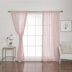 a white chair sitting next to a window covered in pink sheer curtaines on top of a hard wood floor