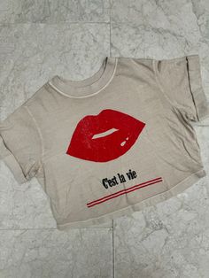 Show off your care free attitude with this Girl Dangerous C'est La Vie Tee with a bold red lips graphic. Perfect for adding a touch of sass to any outfit, this shirt is a must-have for anyone who loves to have fun and live life to the fullest. Color: Sand 100% Cotton Machine wash cold inside out with like colors, tumble dry low Chic Summer Streetwear T-shirt, Chic Cotton T-shirt With Graphic Print, Trendy Relaxed Fit Screen Print Crop Top, Cotton Crop Top With Screen Print, Trendy Relaxed Fit Crop Top With Screen Print, Chic Summer T-shirt For Streetwear, Chic Crop Top For Streetwear, Chic Streetwear Crop Top, Trendy Screen Print Crop Top