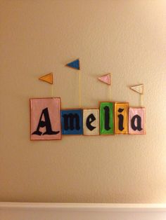 the name amelie spelled with wooden blocks in front of a wall hanging on a wall