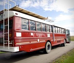 an old red bus is parked on the side of the road with its doors open