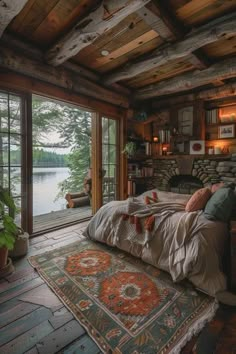 a bedroom with wooden walls and flooring next to a large window overlooking the water