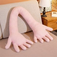 two pink hands are on the back of a couch in front of a table with a lamp