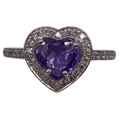 14KT White Gold Finger Size: 6.5 (Ring is size 6.5, but is sizable upon request) Number of Heart Shape Sapphires: 1 Carat Weight: 1.06ct Stone Size: 6.5 x 7.0mm Number of Round Diamonds: 38 Carat Weight: 0.33ctw This lovely ring features a sweet purple heart shaped sapphire center stone. The sapphire is framed by a pave set halo comprised of round brilliant cut diamonds. Additional pave set diamond extends halfway down the band. The ring is set in 14KT White Gold and has a combining total weight Purple Heart Ring Fine Jewelry, Purple Heart Cut Ring With Center Stone, Purple Heart-shaped Fine Jewelry Ring, Heart-shaped Sapphire Ring, Fine Jewelry, Valentine's Day Purple Heart-cut Heart Ring, Round Diamond Ring, Round Rings, Purple Heart, Lovely Ring