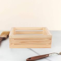 a wooden crate sitting on top of a white counter next to a brush and spatula