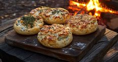 four biscuits sitting on a wooden board in front of an open fire