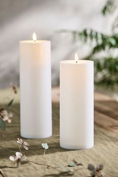 two white candles sitting next to each other