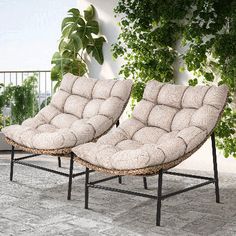 two lounge chairs sitting next to each other in front of a plant covered balcony area