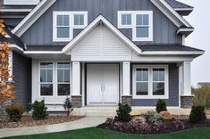 a gray house with white trim and lots of windows on the front door is shown