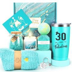 a blue gift hamper with candles, teal towels and other items