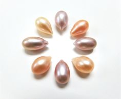 five different colored pearls arranged in a circle on a white surface, with one facing the camera