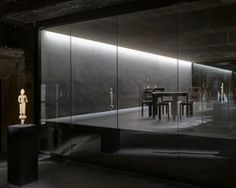 an empty room with glass walls and sculptures