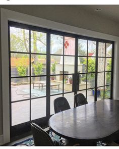 a table and chairs in front of a large window with sliding glass doors leading to a swimming pool