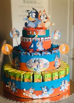 the cake is decorated with cartoon characters and numbers on it's tiered layers