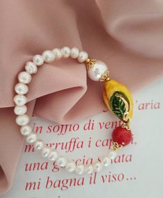 Sicilian bracelet made of: - Freshwater Pearls (6 mm), white color; - Sicily Ceramic Lemon (30 mm x 16 mm); - Mallorca Pearl (12 mm), white color; - Mallorca stone (12 mm), red color. * SHIPPING * Your order will be shipped within 1-3 business days from your purchase. You can choose between 2 shipping methods: STANDARD MAIL (NOT TRACEABLE) It is a cheap and fast shipping method, but NOT TRACEABLE. Chapeau Atelier is not responsible for any postal disruptions, delays or losses. REGISTERED MAIL (T Classic White Beaded Bracelets As Gift, Classic White Beaded Bracelets For Gift, Classic White Bangle Bracelet, Classic White Bracelet For Gift, Classic White Bracelet As A Gift, Classic White Bracelet For Gifts, White Oyster Bracelet Bangle, White Oyster Bracelet, Classic White Pearl Bangle Bracelet