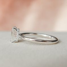 a diamond ring sitting on top of a white cloth covered table next to a pink background