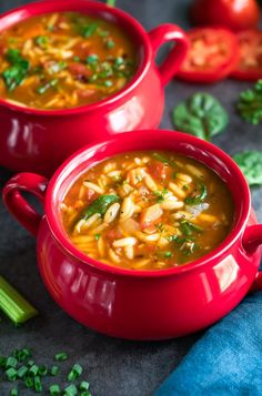 two red bowls filled with pasta soup and garnished with parsley on the side