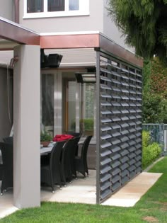 an outdoor dining area with table and chairs under a pergolated roof on the lawn