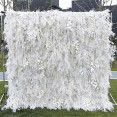 a white backdrop with flowers on it in the middle of a grassy area next to a building