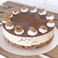 a chocolate cake with white frosting and cookies on top sitting on a wooden table