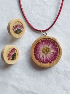 two necklaces with flower designs on them sitting on a table next to a red cord