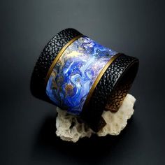 a blue and black cuff bracelet sitting on top of a rock