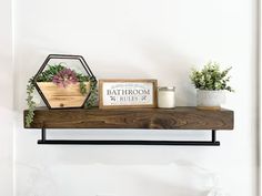 a shelf that has some plants on top of it and a sign with the word bathroom