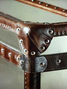 a brown leather bed frame with rivets on the sides and a mirror behind it