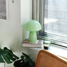 a green lamp sitting on top of a window sill next to a potted plant