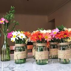 four mason jars filled with colorful flowers on top of a table