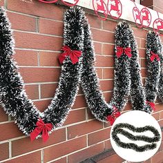 some black and white tinsel wreaths on a brick wall with red bows hanging from them