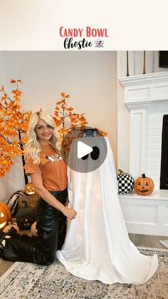 a woman standing next to a fake ghost in a room with pumpkins on the floor