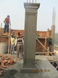 some people are standing around a clock on top of a construction site with brick walls