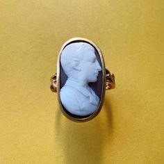 For sale a 18th Century 18K gold empire period cameo ring. This rare ring showcases a remarkable white and brown two-colored hard stone cameo portraying the profile of a distinguished gentleman. The intricacies of his hair, beard, and clothing are nothing short of astonishing, each detail meticulously crafted to perfection. The oversized cameo, measuring an impressive 2,2cm by 1,2cm, transforms this ring into a captivating statement piece when adorned. The sheer size of the cameo ensures that it commands attention, making it the perfect accessory for those who appreciate the grandeur of antique jewelry. The shoulders of the ring are equally enchanting, adorned with sensational floral motifs resembling two delicately intertwined branches of leaves. These intricate details add a touch of rom Antique Carved Signet Ring For Formal Occasions, Classic Carved Signet Ring For Formal Occasions, Elegant Carved Signet Ring For Formal Occasions, Formal Oval Engraved Ring With Intaglio, Heirloom Intaglio Rings For Formal Occasions, Oval Engraved Ring With Intaglio For Formal Events, Antique Cameo Ring Collectible, Vintage Carved Signet Ring For Formal Occasions, Classic Carved Signet Ring For Wedding