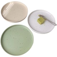 three plates and a fork on a white surface with speckles in the middle